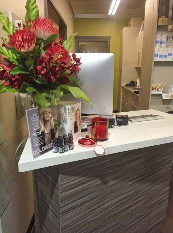 Get Smart Hair Reception desk with flowers, brochures, computer, products and candle on it